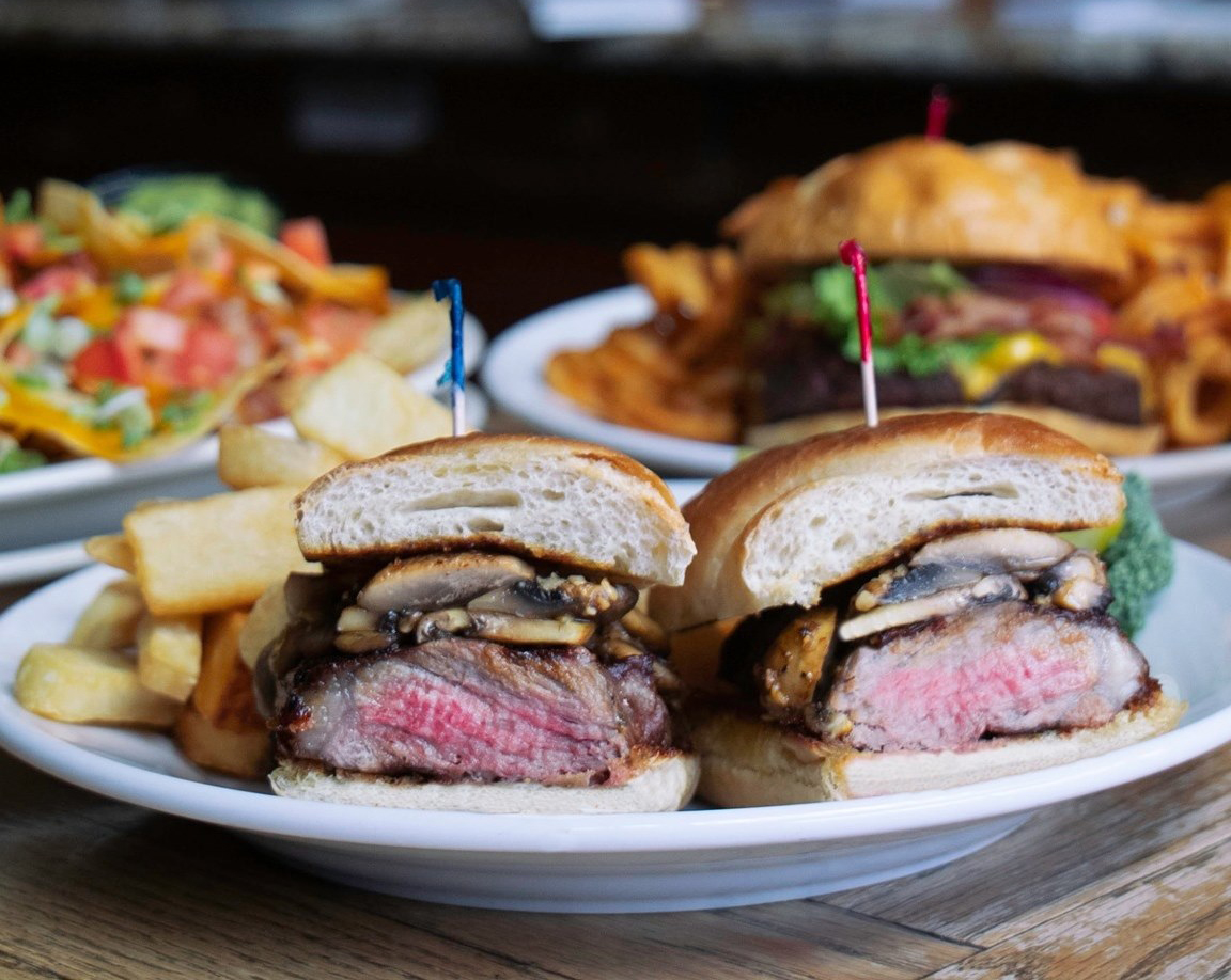 Steak sandwich with fries and other plated foods